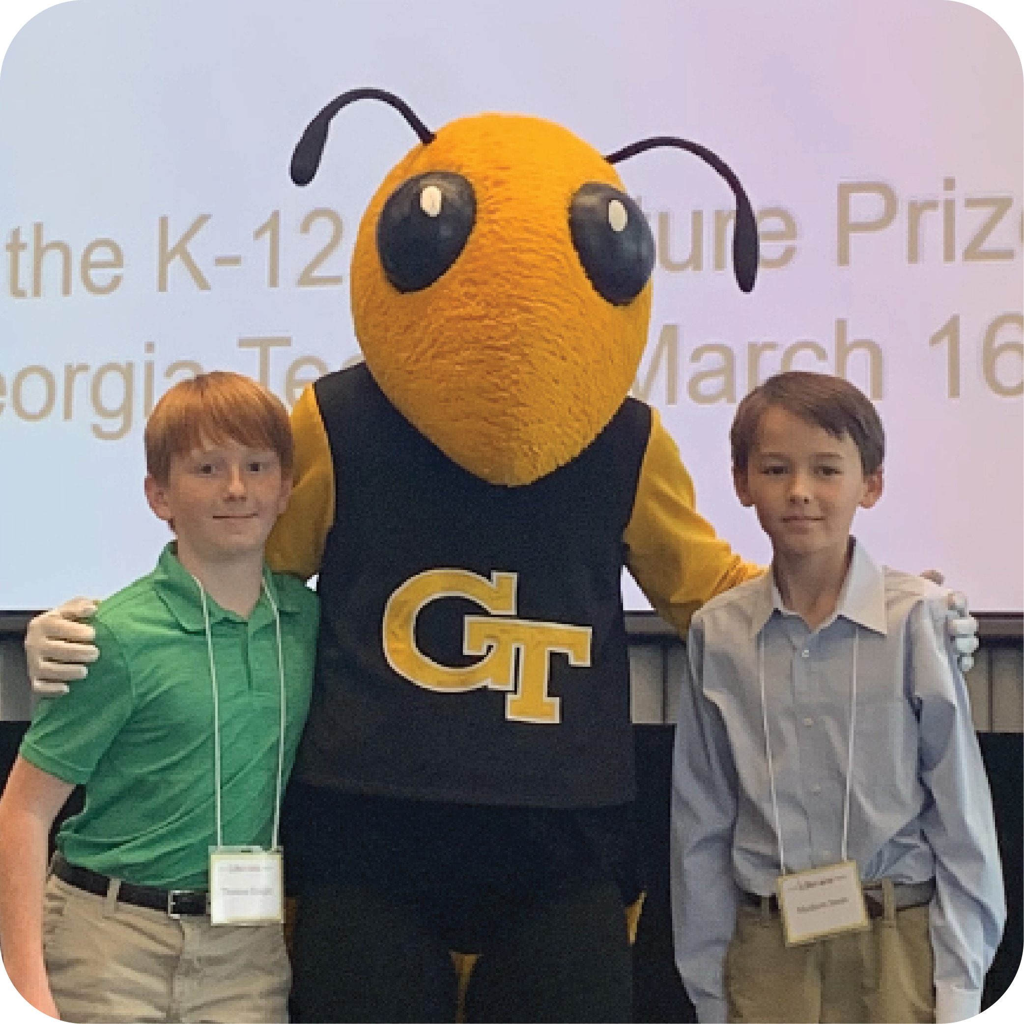 Two smiling students standing next to Buzz (Georgia Tech's yellowjacket mascot).